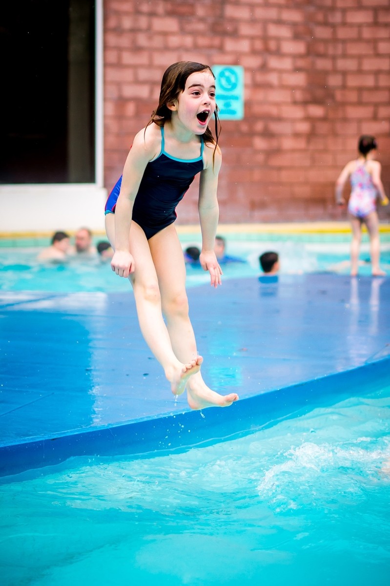 Girl jumping into the outdoor pool.
