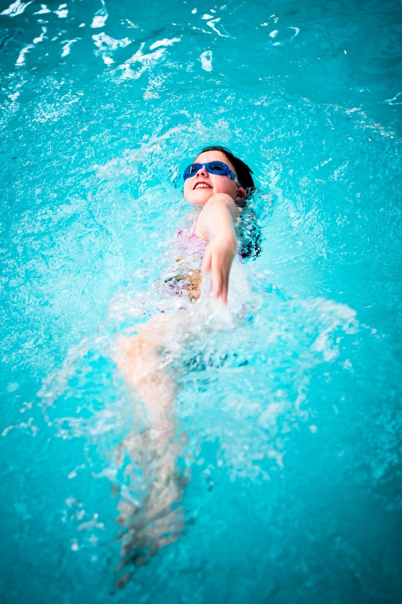 Girl doing a backstroke in the pool.
