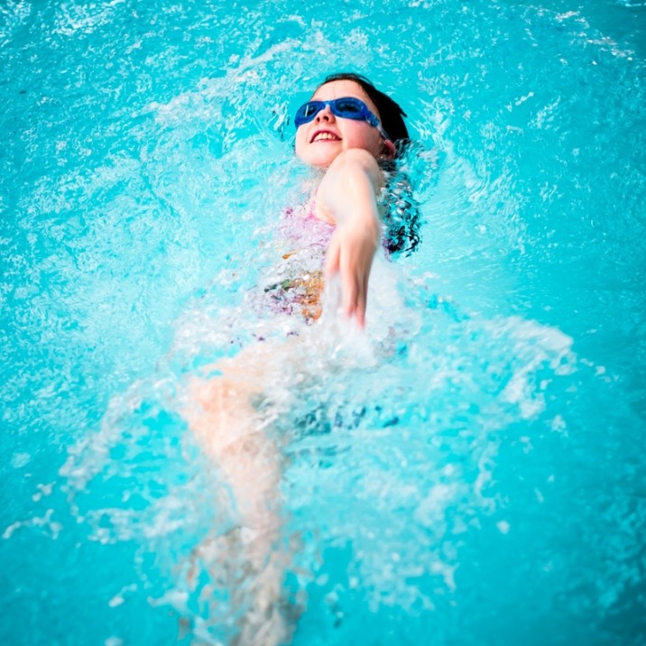 Girl doing a backstroke in the pool.