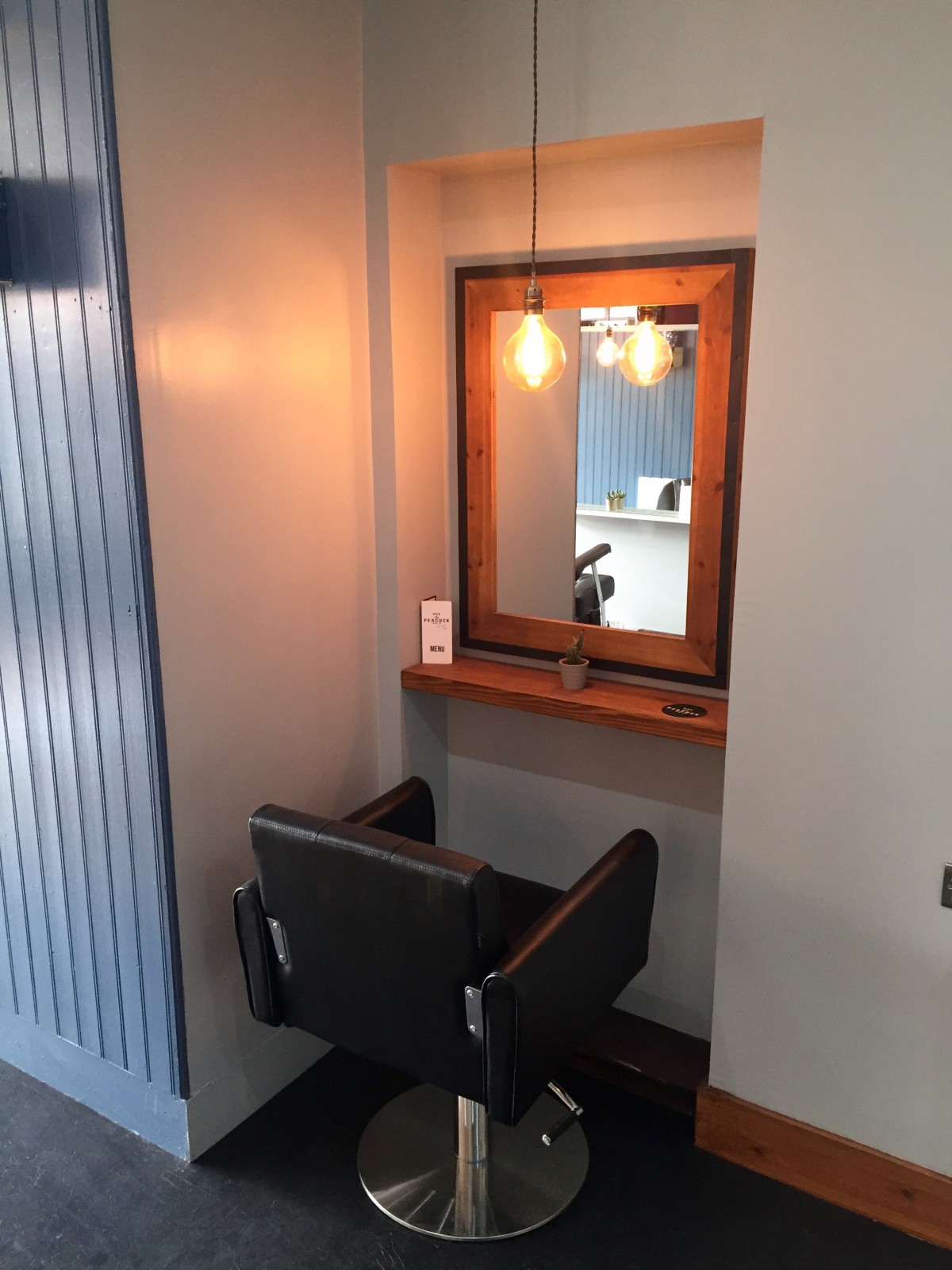 The plush leather salon chairs are illuminated with modern hanging lightbulbs, adding to the cool vibe of Rae Peacocks Hair Salon.