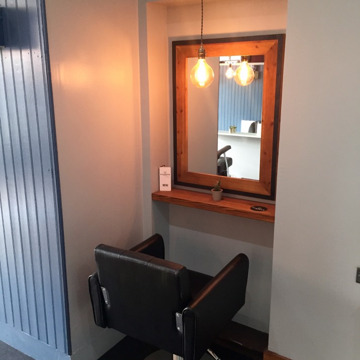 The plush leather salon chairs are illuminated with modern hanging lightbulbs, adding to the cool vibe of Rae Peacocks Hair Salon.