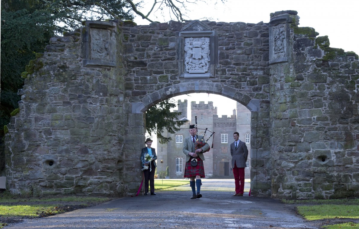 A piper plays underneath the beautiful archway to the drive of Scone Palace.
