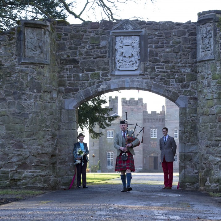A piper plays underneath the beautiful archway to the drive of Scone Palace.