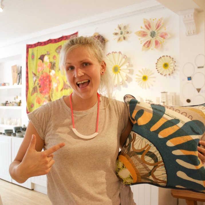 Tayberry Gallery in Perth UK is packed with the best of British, handmade art and design. Tayberry Gallery has been on Princes Street for 7 years, and showcases the work of lots of local creatives. Pictured is Louise (one half of Tayberry) loving the new cushions by Kelly Mackay inspired by Scottish geology, and Beth Lamont's colourful ceramic necklace!