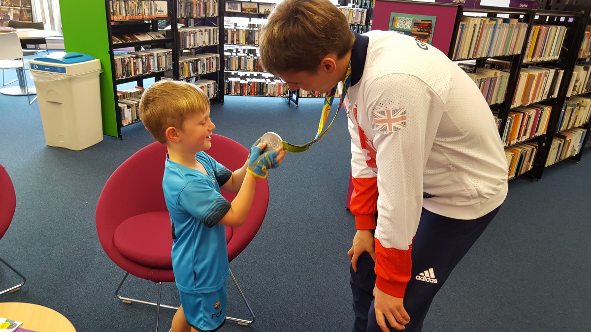 WEEKEND OF SPORT - boy in blue strip holding medal.