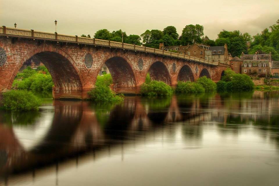 The Old Bridge spanning over the River Tay. The water is so still it shows as a mirrored image reflected in the silvery water.