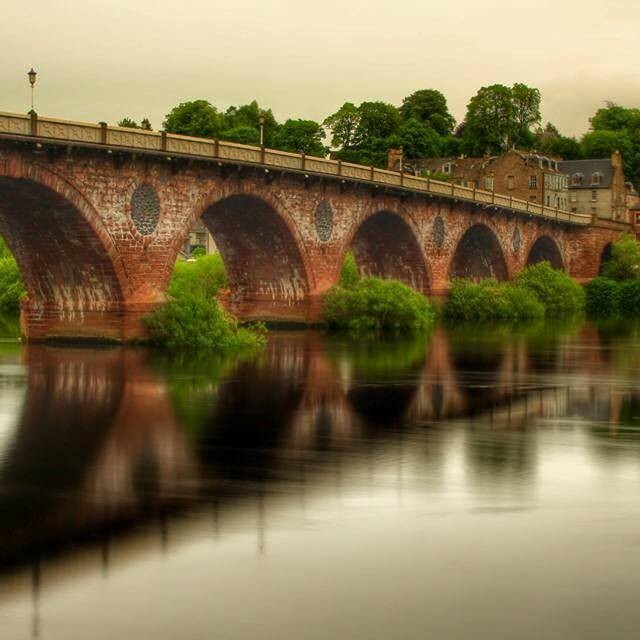 The Old Bridge spanning over the River Tay. The water is so still it shows as a mirrored image reflected in the silvery water.