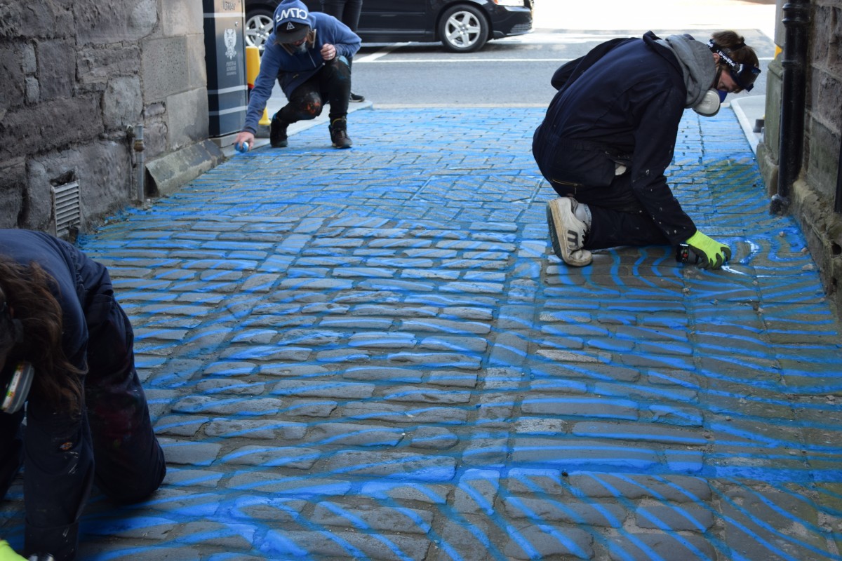 Vennels Guerilla Art Project Water Vennel painting the cobbles blue!