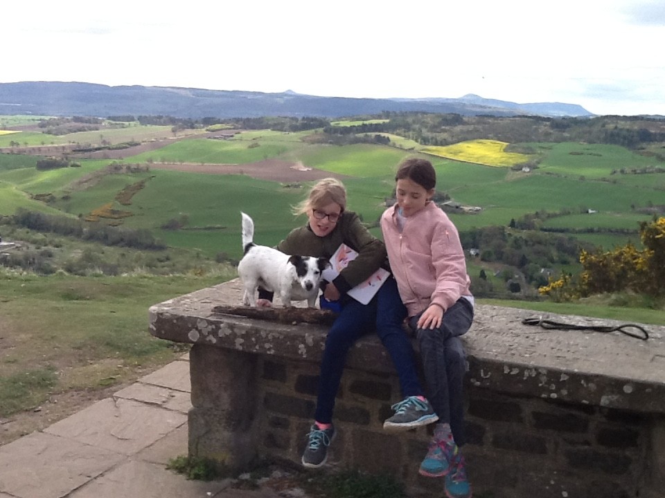 two girls a dog and a stone table that has a crack in it