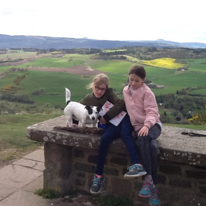two girls a dog and a stone table that has a crack in it