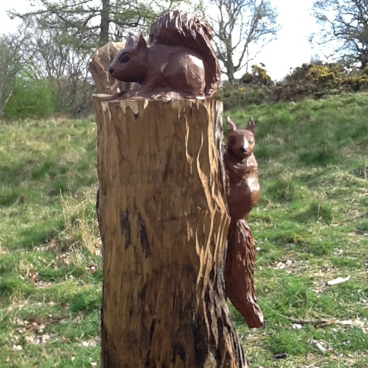 two carved squirrels on a tree stump