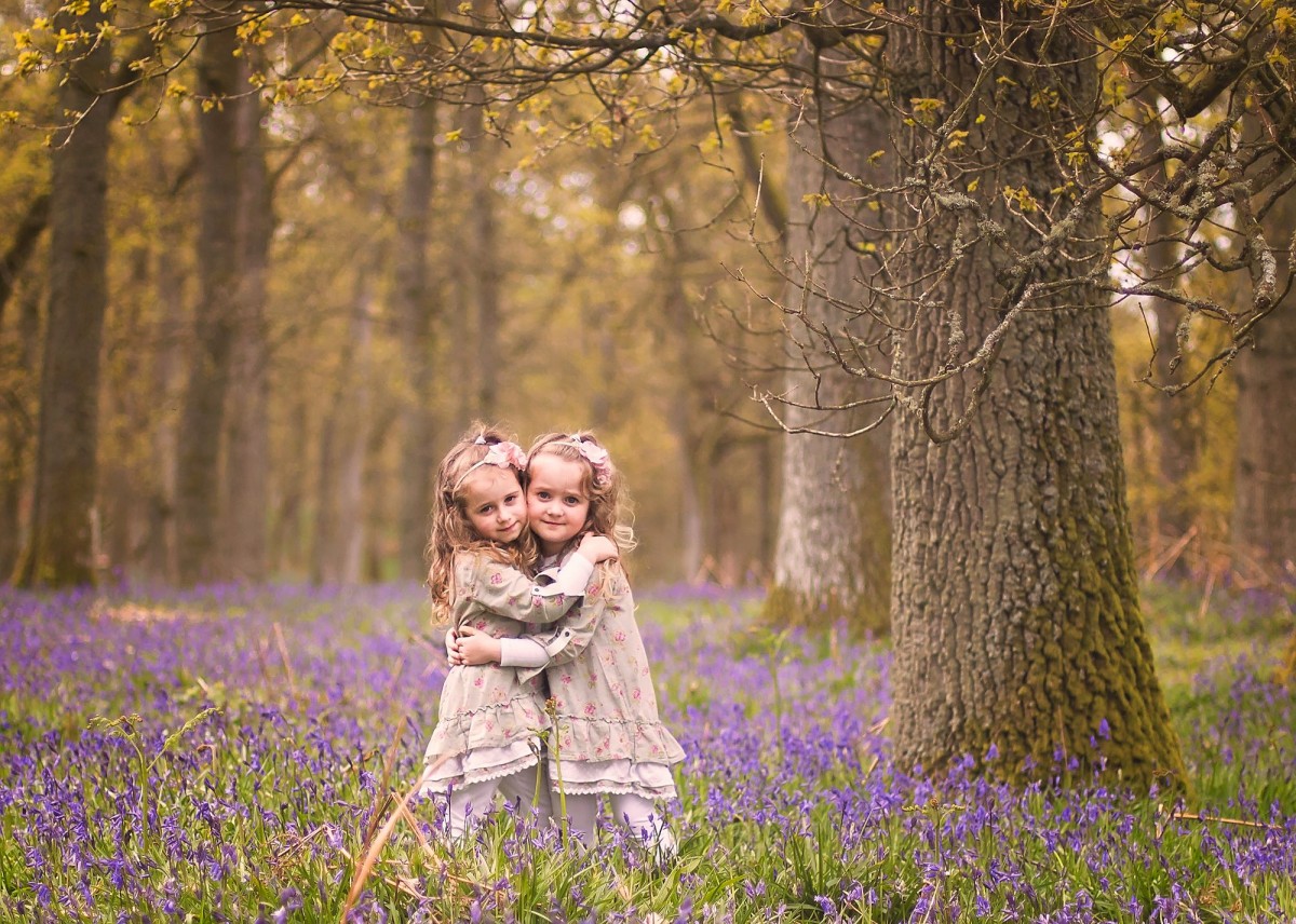 Girls sharing a cuddle with the bluebells in the background!