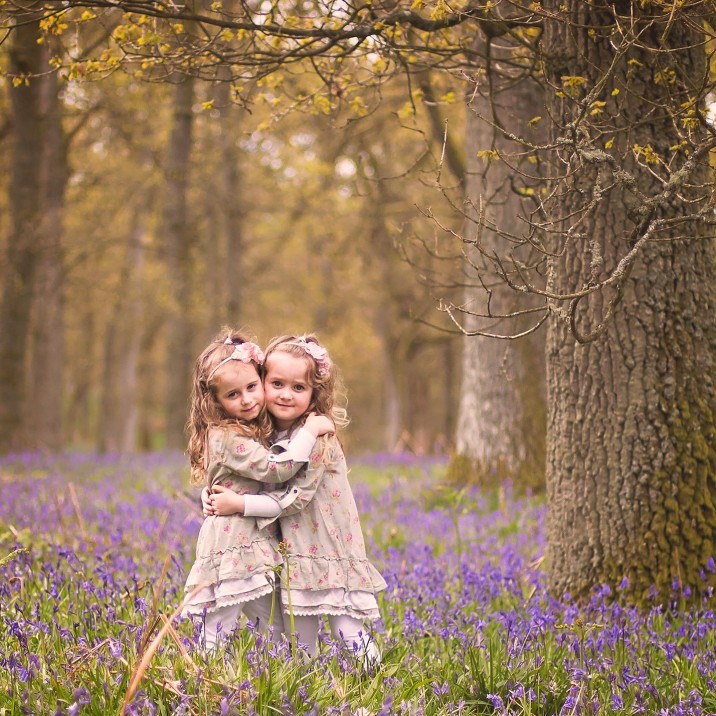 Girls sharing a cuddle with the bluebells in the background!