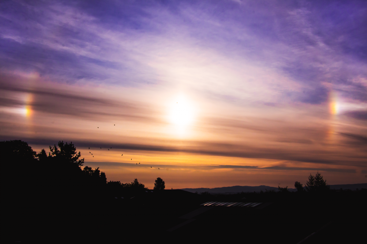 A parhelion, or "sun dog" is captured here. This is an atmospheric optical illusion that consists of a bright spot to one or both sides of the Sun. Sun dogs are a members of the family of halos, and are caused by the refraction of sunlight by ice crystals in the atmosphere.