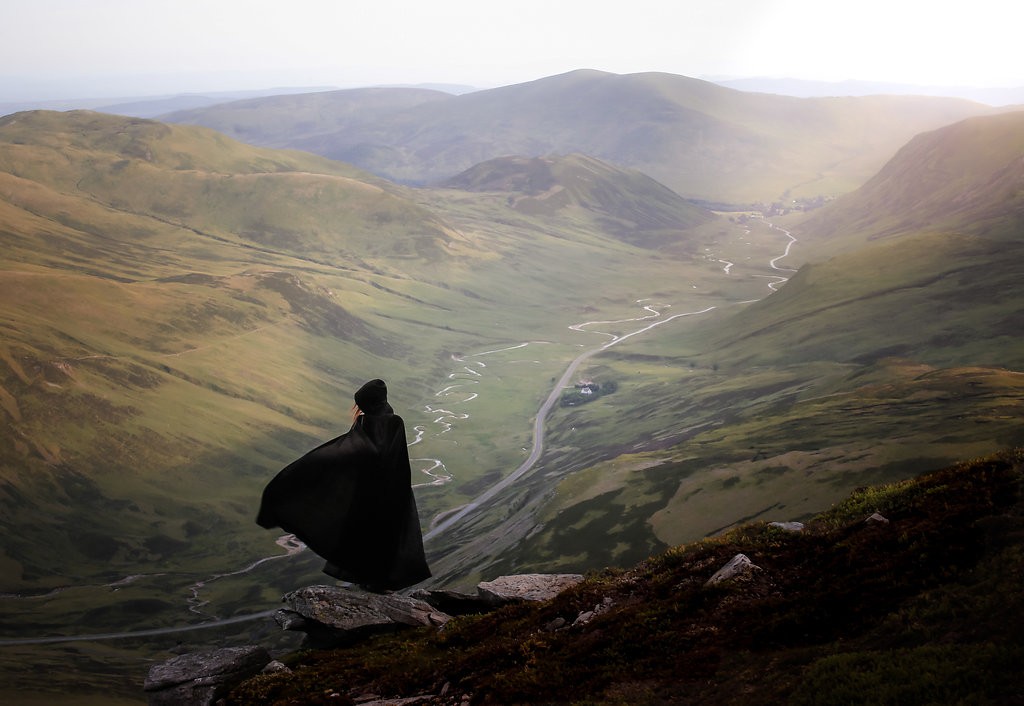 A black caped figure overlooking the beautiful Scottish countryside.