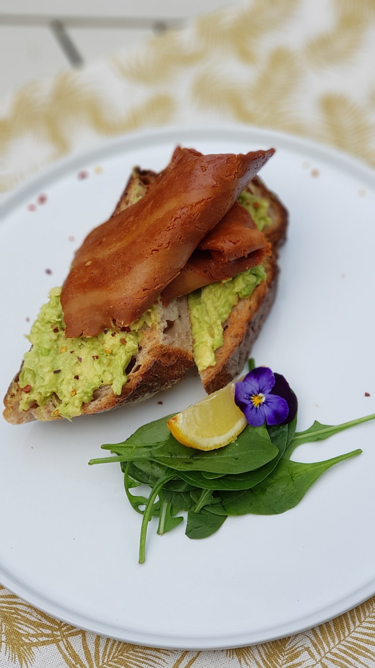 Smashed avocado with cracked black pepper, Maldon sea salt and chilli flakes on lightly toasted sourdough. Sgaia`s Vegan streaky rashers on top.